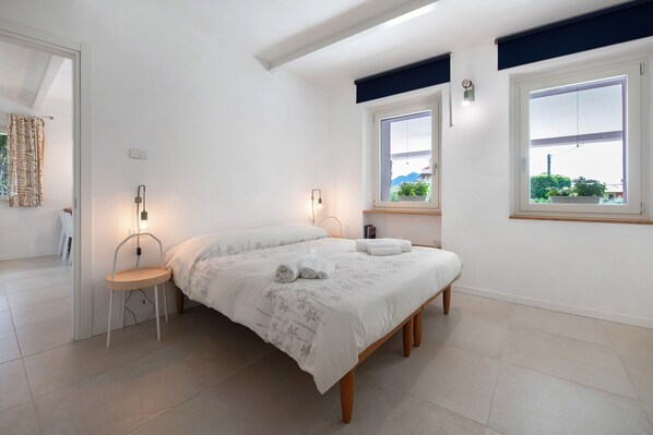Une chambre à coucher avec un lit, des lampes de chevet, une chaise et une fenêtre donnant sur un beau paysage.