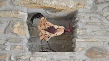 A bird sculpture made of stone slabs, positioned in a niche within a stone wall.