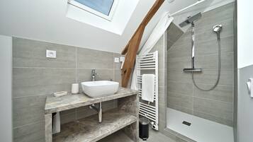Un baño moderno con tragaluz, lavamanos integrado, ducha y perchero.