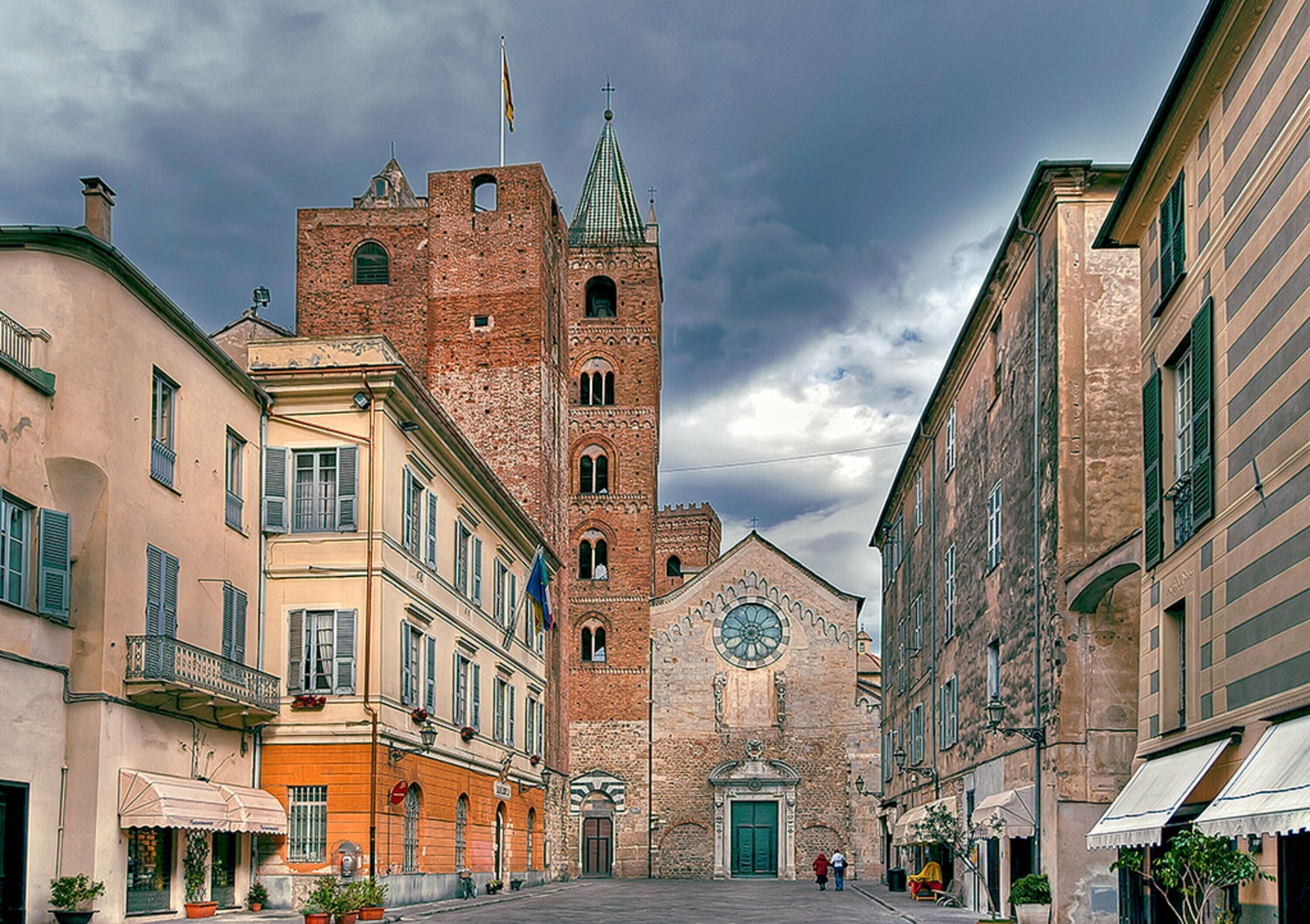 A historic building with a prominent tower and a large circular window, surrounded by other buildings.