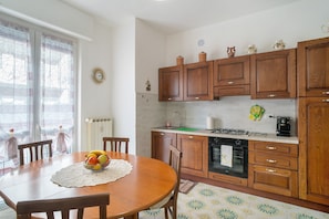 Una cocina con armarios de madera, una estufa y una mesa de comedor con sillas.