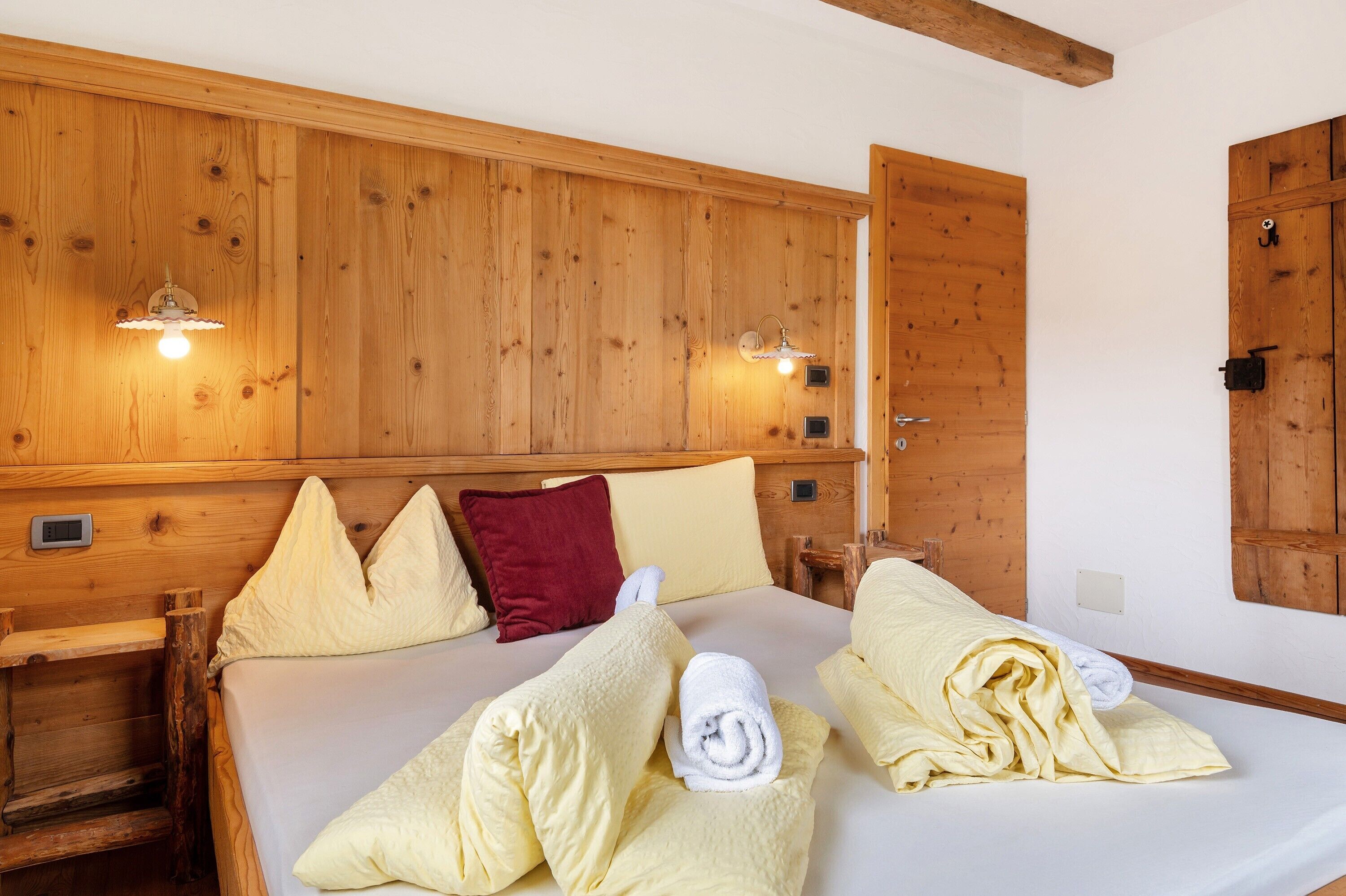 Una habitación con paneles de madera, una cama, almohadas y toallas.