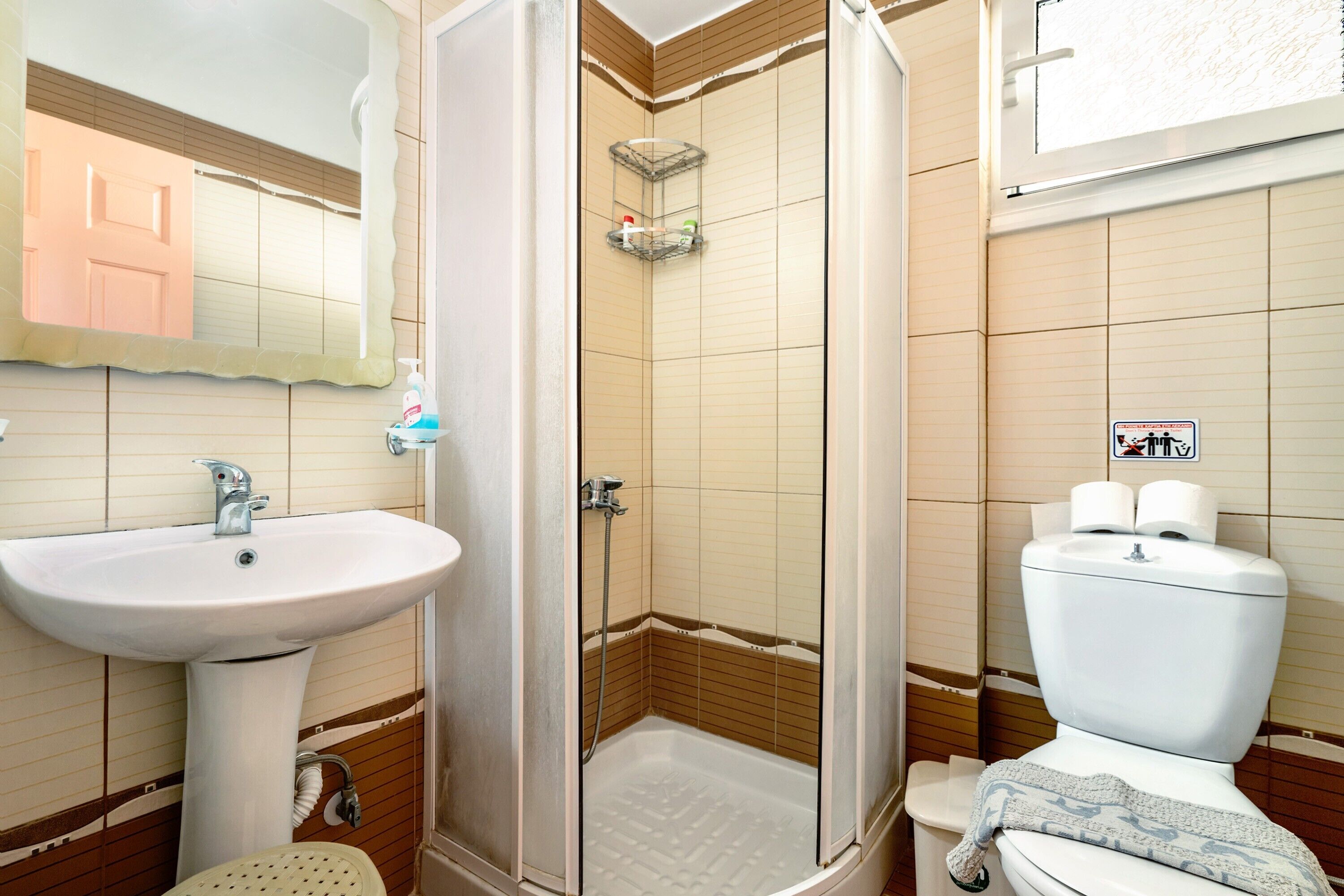 Une salle de bain équipée d’un lavabo, de toilettes, d’une douche et d’un miroir.
