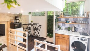 A compact kitchen with a microwave, toaster, and coffee maker, a dining area with chairs, and a washing machine. - Apartment 'Duplex Parisien Charmant Métro13' with Wi-Fi (Paris)