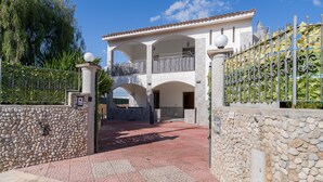 A two-story building with a stone wall, a metal gate, and a paved entrance area. - Villa with Jacuzzi & Fitness Area – Private Spaces & Exclusive Areas – Arenella Mare (Arenella)