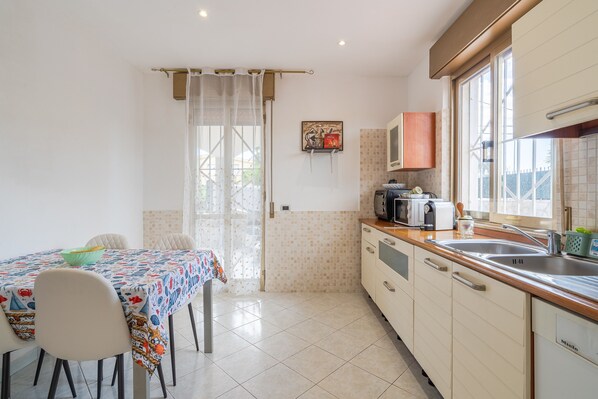 A kitchen with a dining table, chairs, a sink, and a window.