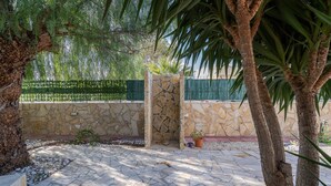 A stone patio with a stone wall, a gate, and a palm tree. - Villa with Jacuzzi & Fitness Area – Private Spaces & Exclusive Areas – Arenella Mare (Arenella)