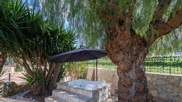 A hot tub with stone steps, a tree, and an umbrella in a garden setting. - Villa with Jacuzzi & Fitness Area – Private Spaces & Exclusive Areas – Arenella Mare (Arenella)