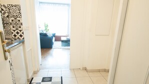 A hallway with a patterned rug, a radiator, and a door leading to a room.