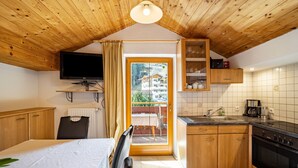 Una habitación con cama, televisión, cocina con estufa y vistas a través de una puerta.