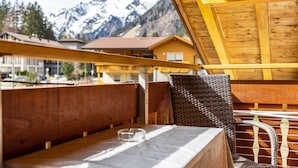 Interior de madera con una mesa y sillas, vista a las montañas y estructura de techo de madera.