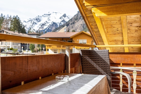 Un intérieur en bois avec une table et des chaises, une vue sur les montagnes et une structure de plafond en bois.