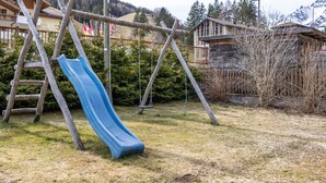 Un parque infantil con un tobogán, columpios y una estructura de madera.