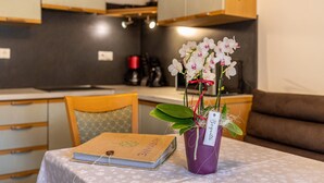 Una pequeña mesa con un libro, una maceta morada con flores blancas y una etiqueta.
