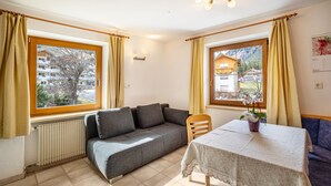 Une pièce avec un canapé, une table recouverte d’une nappe et une chaise.