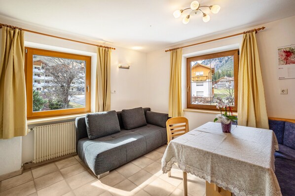Una habitación con un sofá, una mesa con mantel y una silla.