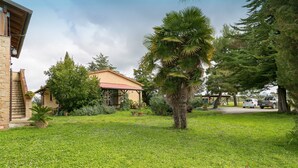 A well-maintained garden with a variety of plants and a building with a red roof. - Agriturismo "Il Nazareno - Il Coppaio" with Shared Pool and Wi-Fi (cecina)