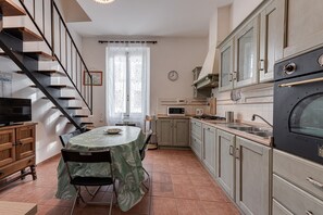 A kitchen with a dining table, chairs, a microwave, stove, and cabinets.
