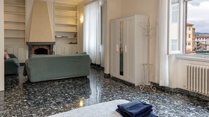 Hotellihuone, jossa on takka, sohva, vaatekaappi ja ikkunasta avautuva näkymä.