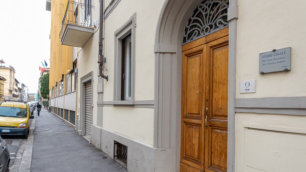 Katu, jolla on keltainen taksi, puiset pariovet ja kyltti, jossa lukee: ”STUDIO LEGALE”.