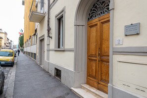 A street with a yellow taxi, a wooden double door, and a sign reading 'STUDIO LEGALE.'