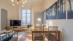 A modern living room with a TV, dining table, chairs, and artwork on the wall.