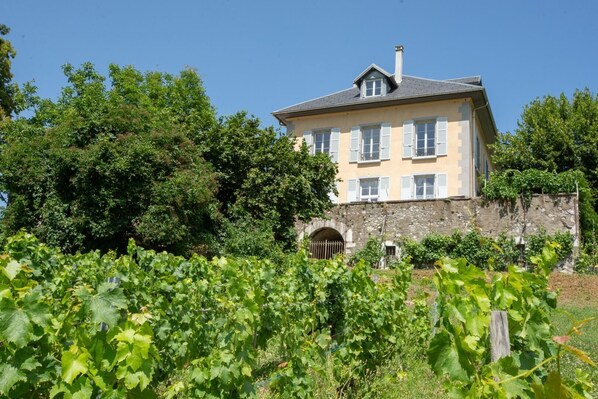 A large, two-story building with a stone wall and a large arched entrance.