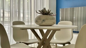 A round table with a central decorative stone, surrounded by white chairs, in a room with a blue accent wall and sheer curtains. - N276 - Numana, Spiaggiola beach front apartment (Numana)