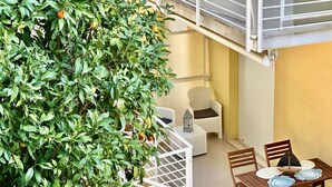 A balcony with a white railing, a table with chairs, and a potted plant with green leaves and oranges. - N276 - Numana, Spiaggiola beach front apartment (Numana)