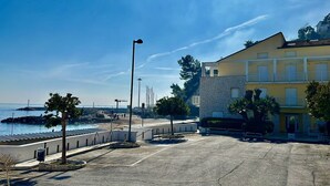 A coastal building with a stone facade, a parking area, and a clear view of the sea. - N276 - Numana, Spiaggiola beach front apartment (Numana)