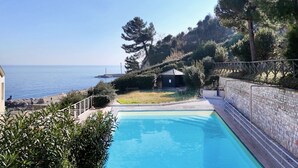 A swimming pool with a view of the sea, surrounded by greenery and a stone wall. - N276 - Numana, Spiaggiola beach front apartment (Numana)
