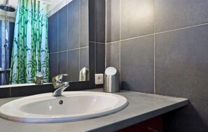 A bathroom with a white sink, dark tiles, a mirror, and a bamboo curtain. - Cozy home in Eyragues (Eyragues)