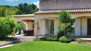 A two-story building with a tiled roof, arched doorways, and a covered patio area with outdoor seating. - Luxurious home in Mouries with private swimming pool, can be inside or outside (Mouries)