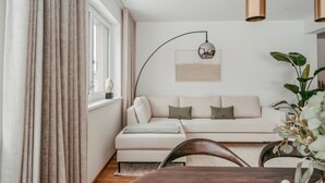Moderni olohuone, jossa on sohva, ruokapöytä ja lattiavalaisin.
