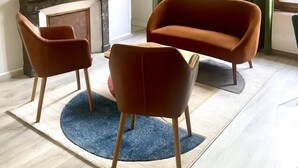 Un saló modern amb un sofà, dues butaques, una televisió i obres d'art a les parets.