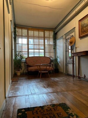 Una habitación con piso de madera, un sofá, una mesita y una ventana con vista a edificios.