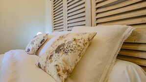 Un llit amb almoinals de motius florals i un capçal de fusta.