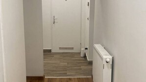 A hallway with a wooden floor, a white door, and a white radiator. - Cozy 3BR Apt. Wien Simmering (Wien)