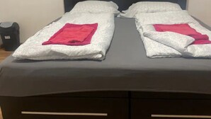 A double bed with white bedding and a pink towel, a black headboard, and a trash bin. - Cozy 3BR Apt. Wien Simmering (Wien)