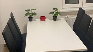 A dining table with four black chairs, two potted plants, and a red vase. - Cozy 3BR Apt. Wien Simmering (Wien)