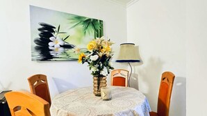 Una mesa de comedor con mantel estampado, un jarrón con flores y un cuadro en la pared.