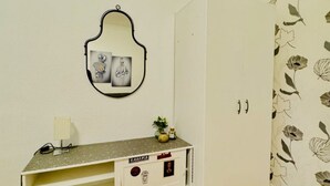 Una habitación con un espejo, un mueble pequeño con estampado floral y un papel tapiz con diseño floral.