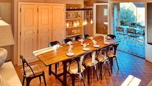 Un comedor con mesa y sillas de madera, una estantería y vista a un patio exterior.