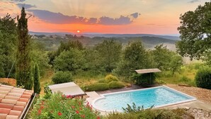 Una piscina con vistas a la puesta de sol sobre un paisaje montañoso.