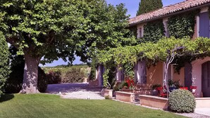 A residential property with a well-maintained lawn, a large tree, and a house with a tiled roof and a covered porch. - Amazing home in Violes (Violes)
