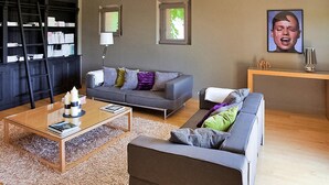 A modern living room with a grey sofa, a coffee table, and a bookshelf. There are two windows providing natural light. - Amazing home in Violes (Violes)