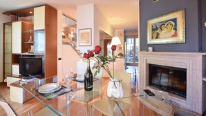 A modern living room with a glass coffee table, a fireplace, and a dining area with a set table. - Awesome home in Bergamo with WiFi (Bergamo)