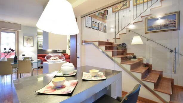 A modern kitchen with a dining area, a staircase with glass railings, and artwork on the walls. - Awesome home in Bergamo with WiFi (Bergamo)