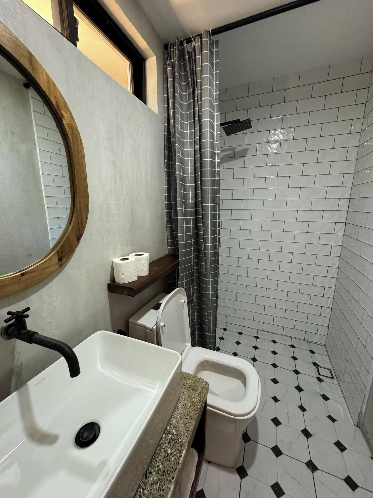 Ein Badezimmer mit weißem Waschbecken, Toilette und Duschbereich mit kariertem Vorhang.