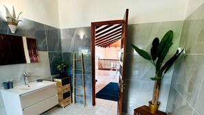 A modern bathroom with a white sink, wooden vanity, and a large mirror. - Le Domaine du Val de l'Orge (Vieux-Habitants)